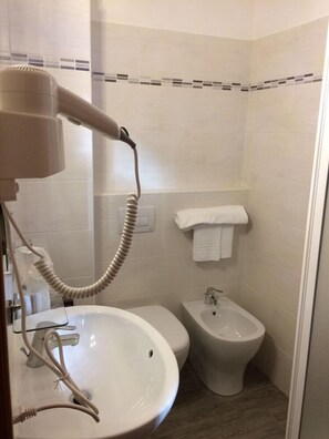A bathroom with a sink, toilet, bidet, and a hairdryer. - Twelve Hotel (Moncalieri)