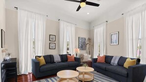 A modern living room with two sofas, a coffee table, and a TV stand. - Fab Marigny | 2BD Flat | Close to French Quarter (New Orleans)