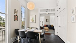 A dining area with a table set for four, black chairs, and a hanging light fixture. - Fab Marigny | 2BD Flat | Close to French Quarter (New Orleans)