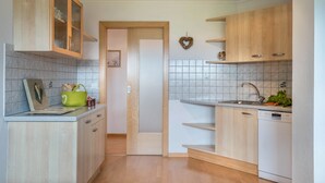 Una cocina con armarios de madera, lavavajillas blanco y salpicadero de azulejos.