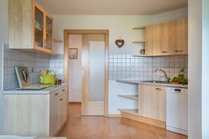 A kitchen with wooden cabinets, a white dishwasher, and a tiled backsplash.