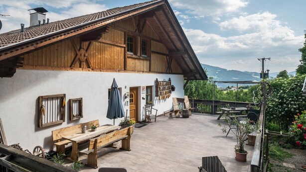 Un edificio rústico de madera con techo inclinado, una banca de madera y una mesa al exterior.