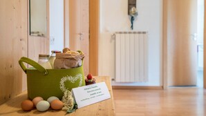 Une pièce avec un plancher en bois, un sac en toile vert contenant divers objets, et un panneau posé sur une table.