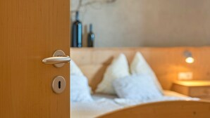 Une porte en bois, dotée d’un trou de serrure et d’une poignée, qui donne sur un lit recouvert de draps et d’oreillers blancs.