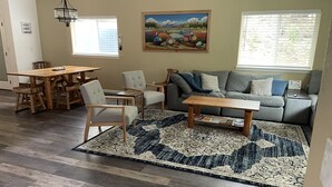 Una sala de estar con una mesa de comedor de madera, sillas, un sofá y una mesa auxiliar.