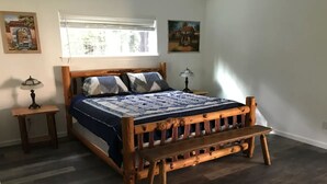 Un dormitorio con una cama de madera, una mesita de noche, una lámpara y un ventanal con persianas.