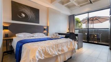 Une chambre d’hôtel avec un lit, un bureau et un balcon équipé d’un parasol.