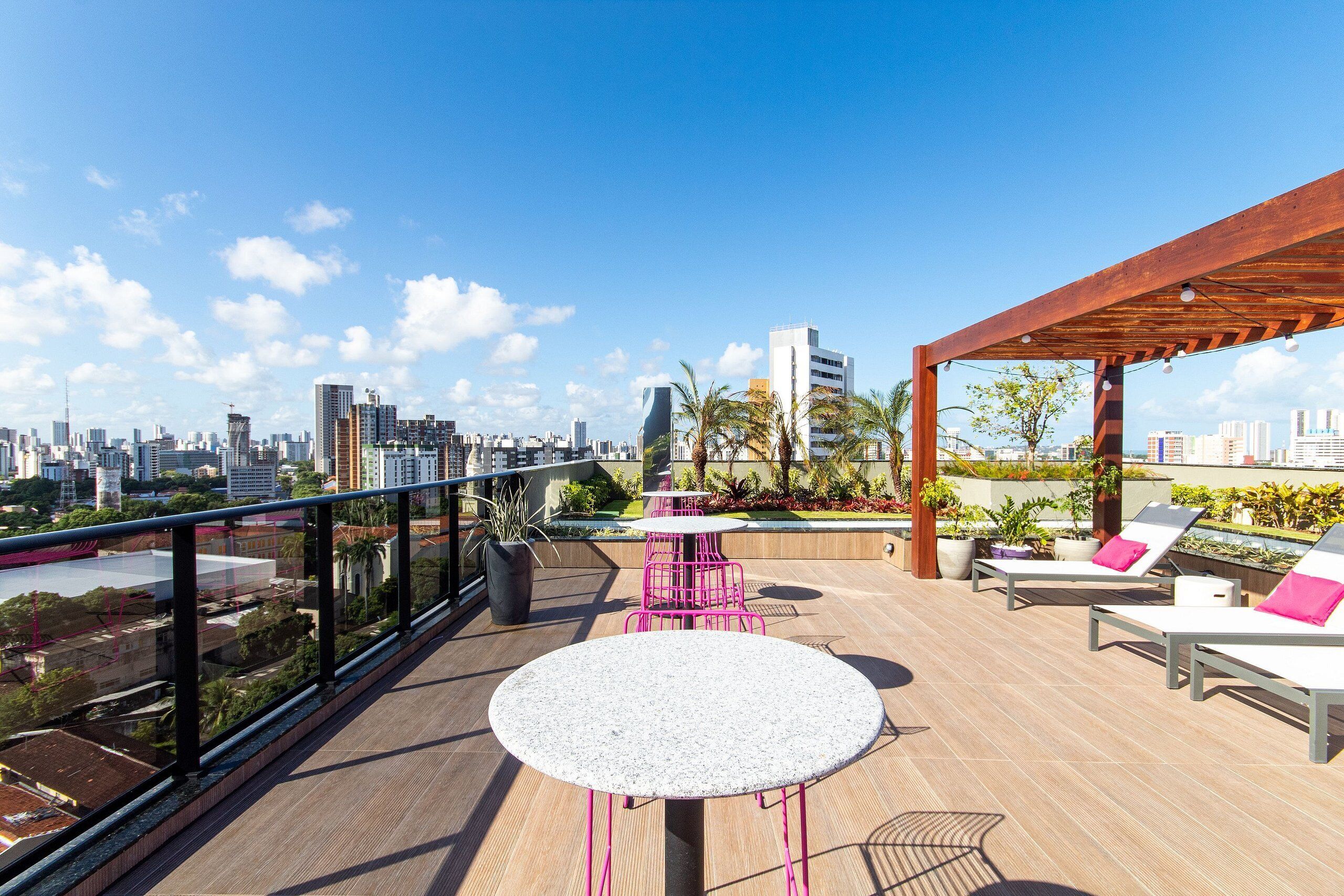 Une terrasse sur le toit offrant une vue sur la ville, avec des sièges extérieurs et une pergola.