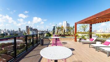 Une terrasse sur le toit offrant une vue sur la ville, avec des sièges extérieurs et une pergola.