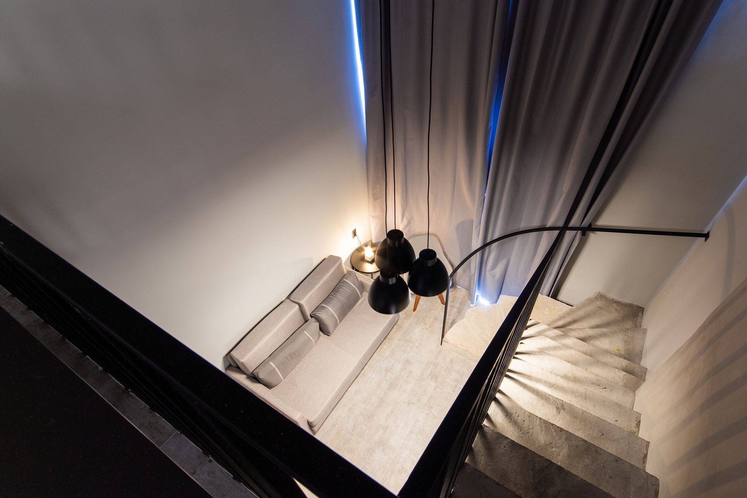 Un escalier avec un espace de repos rembourré en bas, un luminaire et un rideau.