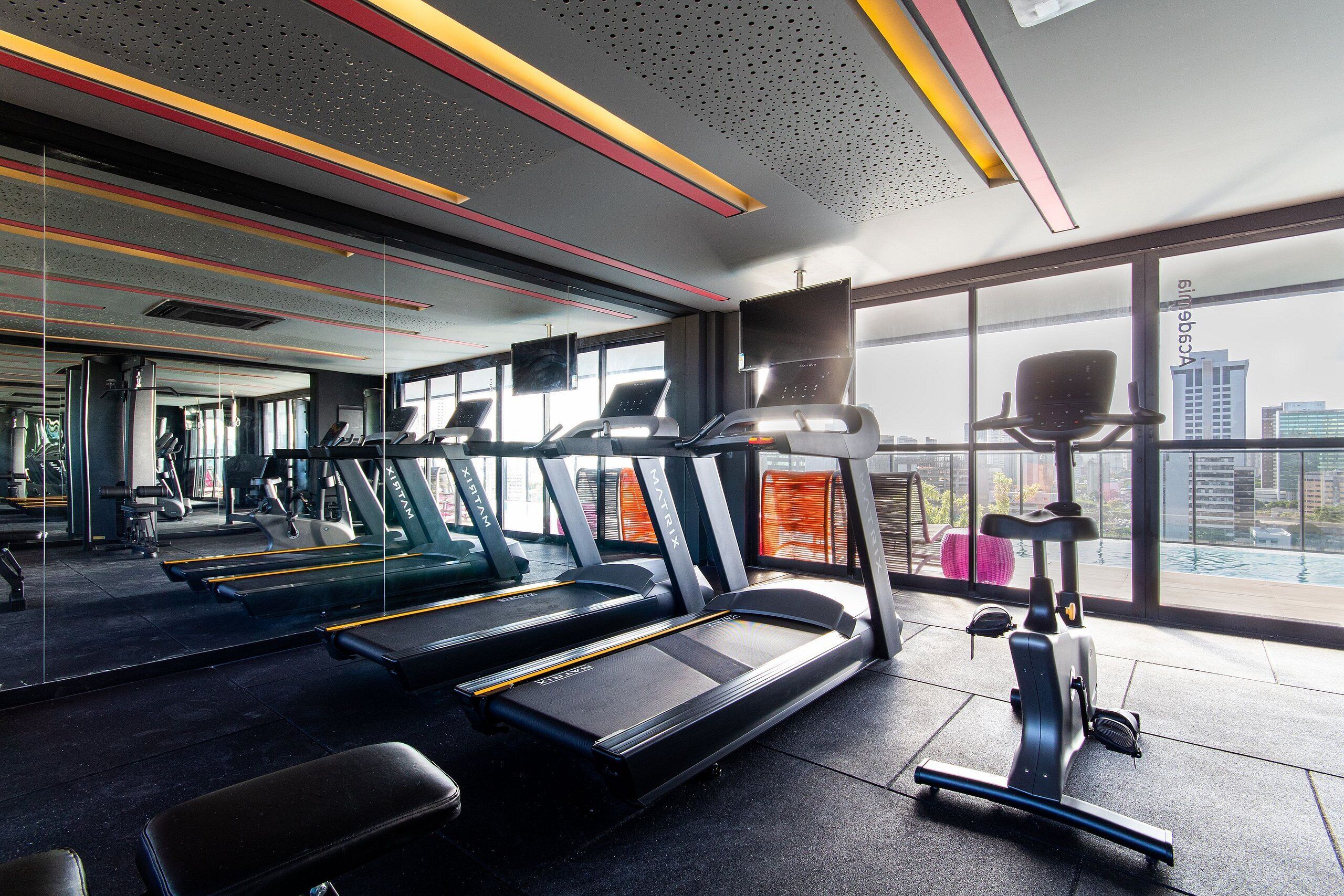 Un gimnasio moderno con cintas de correr, bicicletas estáticas y una máquina de remo.