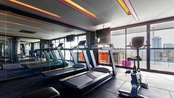 Un gimnasio moderno con cintas de correr, bicicletas estáticas y una máquina de remo.