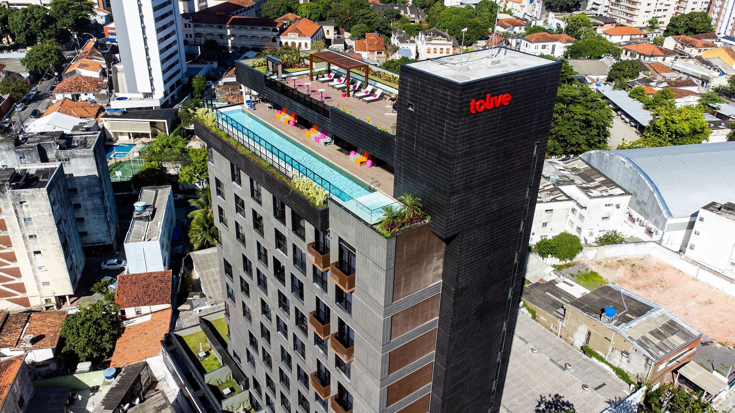 Un edificio de gran altura con piscina y zona de descanso en la azotea.