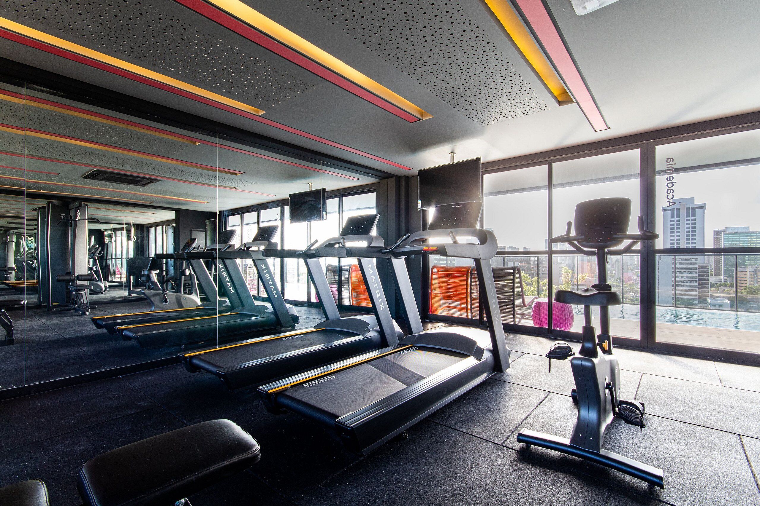 Un gimnasio con cintas de correr, bicicletas estáticas y una máquina de remo.