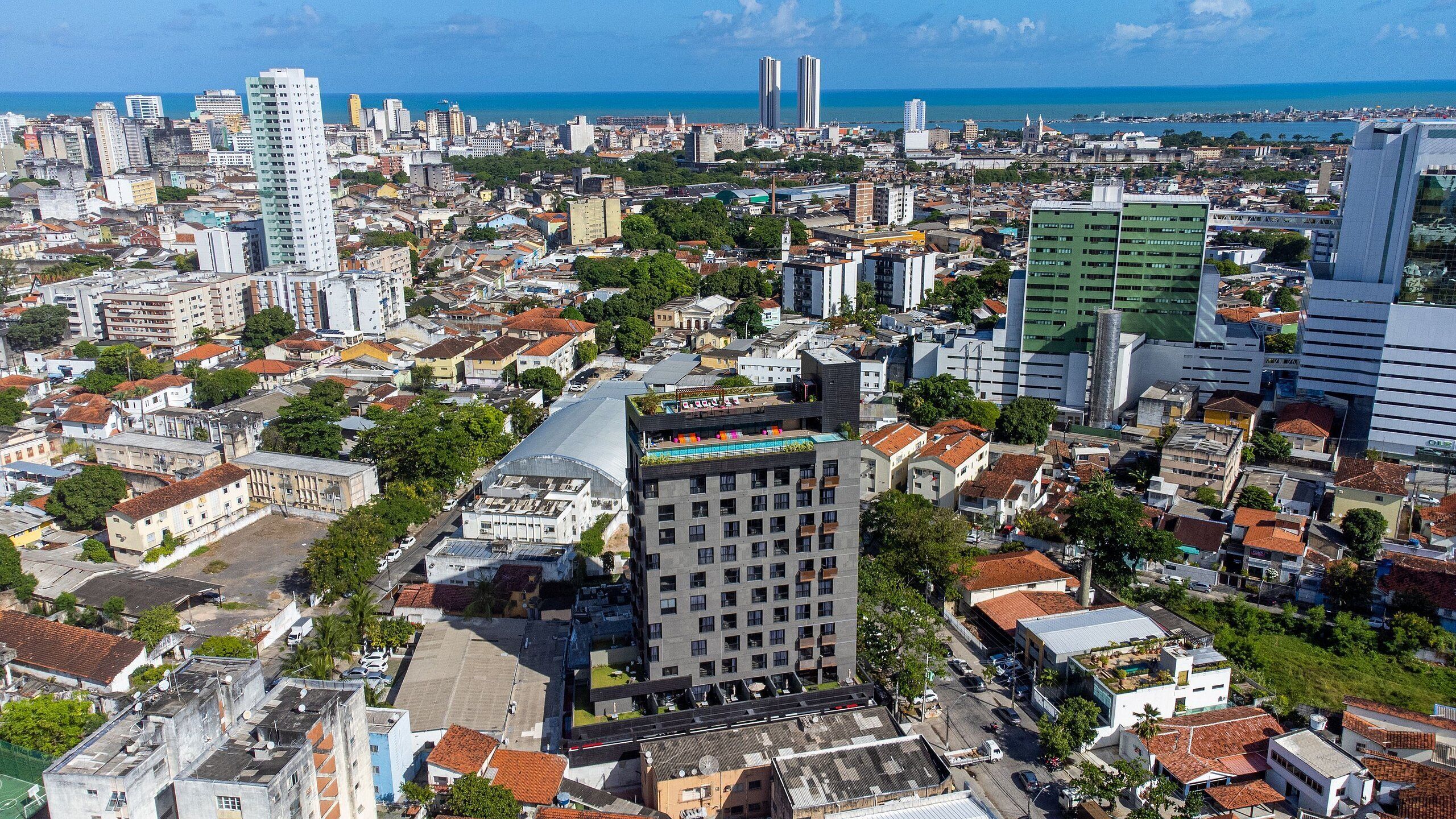 An urban landscape with a mix of residential and commercial buildings, including a prominent hotel with a rooftop pool.