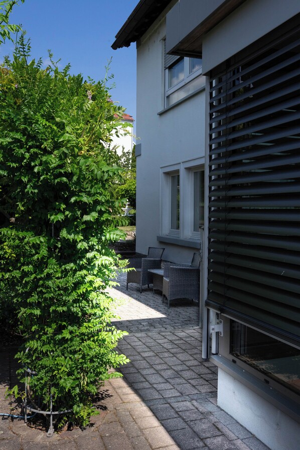 A residential building with a paved patio, a small garden, and a window with blinds. - Friendly, wheelchair-accessible vacation rental in Lengfurt: The Berger Family (Triefenstein)