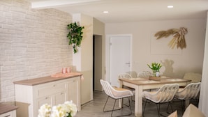 A modern kitchen with white cabinetry, a wooden countertop, and a dining area with wicker chairs and a wooden table. - Friendly, wheelchair-accessible vacation rental in Lengfurt: The Berger Family (Triefenstein)