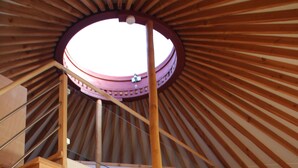 Een houten interieur met een rond dakraam, een trap en een bank.