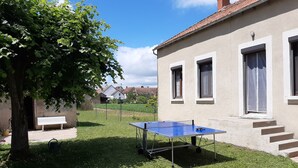 A courtyard with a ping pong table, a bench, and a tree.