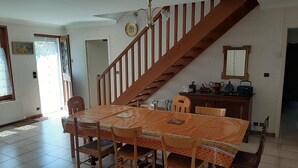 A dining area with a wooden staircase, a table with a patterned tablecloth, and chairs.