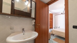 A bathroom with a white sink, wooden door, and a mirror above it.