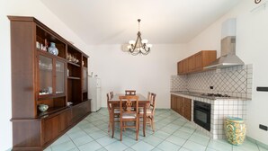 A kitchen with a dining table, chairs, a chandelier, cabinets, a stove, and a refrigerator.