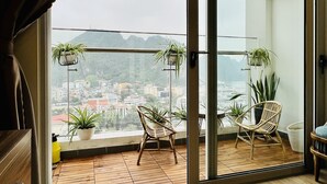 A balcony with wooden flooring, two wicker chairs, and potted plants.