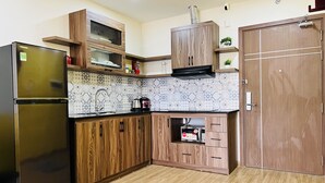 A compact kitchen with wooden cabinets, a refrigerator, a microwave, and a small countertop area.