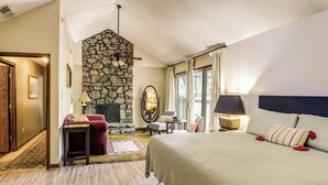 Een slaapkamer met een stenen openhaard, een bed met hoofdeinde, een bureau en een stoel.