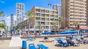 A beachfront hotel with multiple balconies, a boardwalk, and beach chairs. - Los Ranchos 4-3 Apartment Levante Beach (Benidorm)