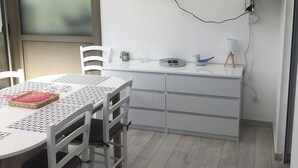 Een moderne keuken met een witte tafel, stoelen en een aan de muur bevestigde televisie.