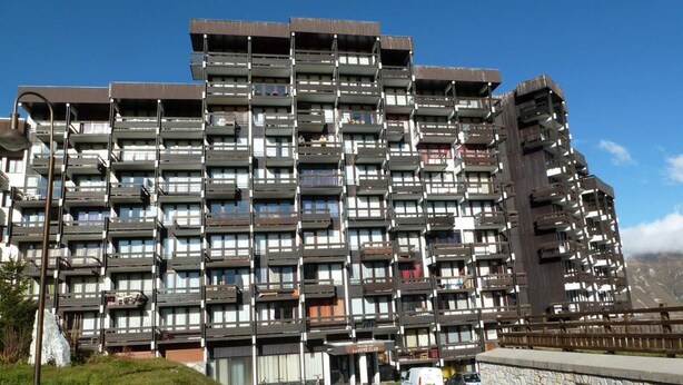 A multi-story hotel with balconies, a stone facade, and a clear sky. - 100m from resort center, balcony, tv, ski locker, 21m², Tignes (Tignes)