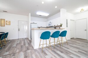 Une cuisine moderne avec des armoires blanches, un comptoir en bois et des tabourets de bar de couleur turquoise.