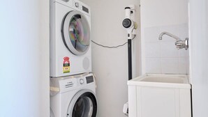 A laundry area with stacked washing machines and a wall-mounted dryer.