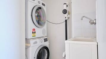 A laundry area with stacked washing machines and a wall-mounted dryer.