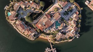 Luchtbeeld van een kustresort met meerdere gebouwen, een zwembad en boten afgemeerd aan een steiger.