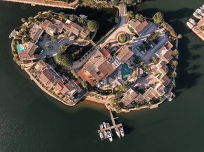 Une vue aérienne d’une station balnéaire comprenant plusieurs bâtiments, une piscine et des bateaux amarrés à un quai.