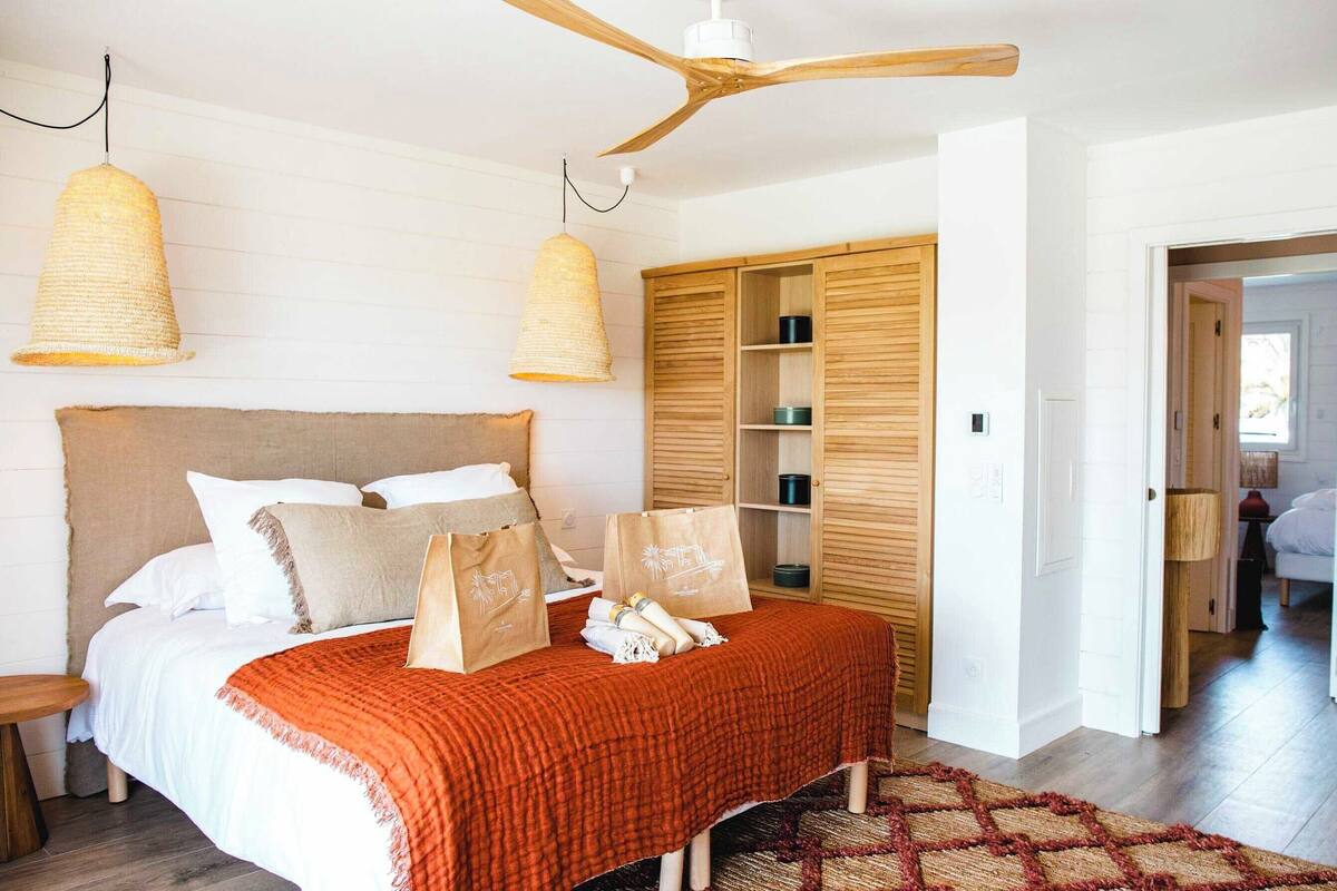 Ein Schlafzimmer mit Bett, Holzschrank, Deckenventilator und Hängeleuchten.