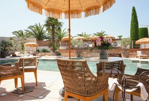 An outdoor pool area with wicker furniture, umbrellas, and a flower arrangement.
