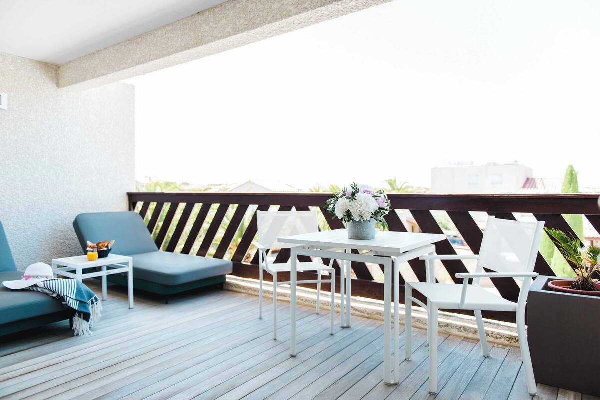 Ein Balkon mit einer Couch, Stühlen, einem Tisch und einem Blumentopf.