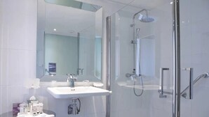 Ein modernes Badezimmer mit einer gläsernen Duschkabine, einem weißen Waschbecken und einem großen Spiegel.
