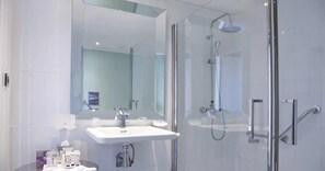 Een moderne badkamer met een douchecabine van glas, een wit wastafelmeubel en een grote spiegel.