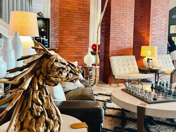 A modern living room with a brick wall, a chessboard, and a white sofa.