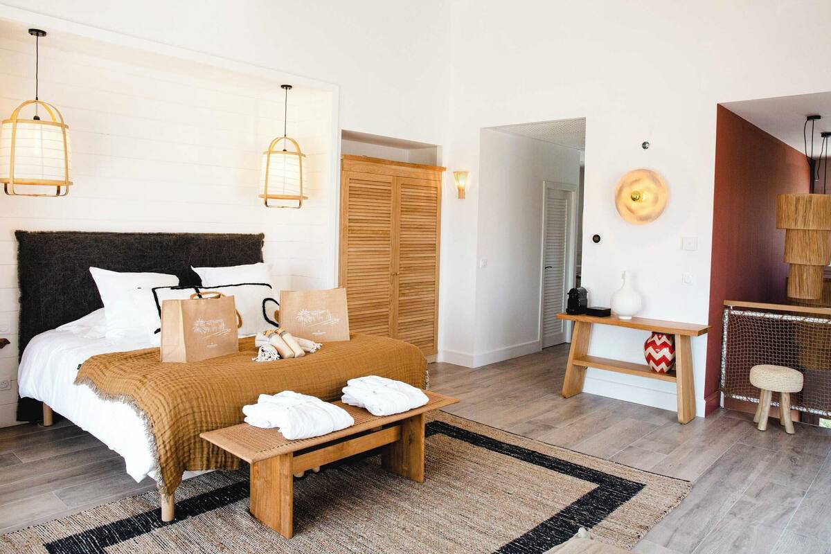 Ein Schlafzimmer mit einem Bett, Nachttischen, einer hölzernen Bank, einem Schreibtisch und einem Kleiderschrank.