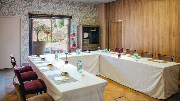 Ein Konferenzraum mit einem langen Tisch, Stühlen und einem Projektor.