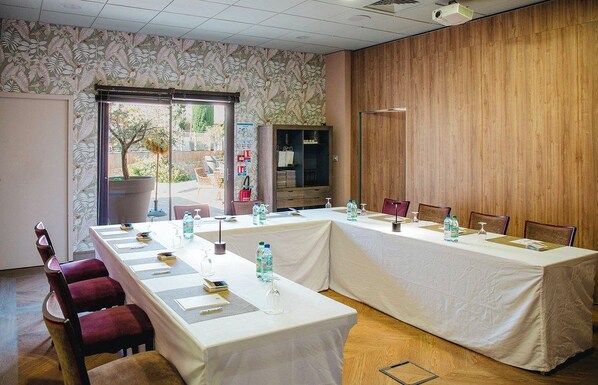 Een vergaderzaal met een lange tafel, stoelen en een beamer.