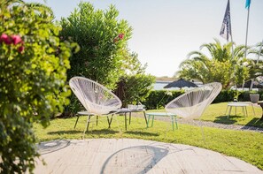 Een terras met twee witte stoelen, een tafeltje en een vlag.