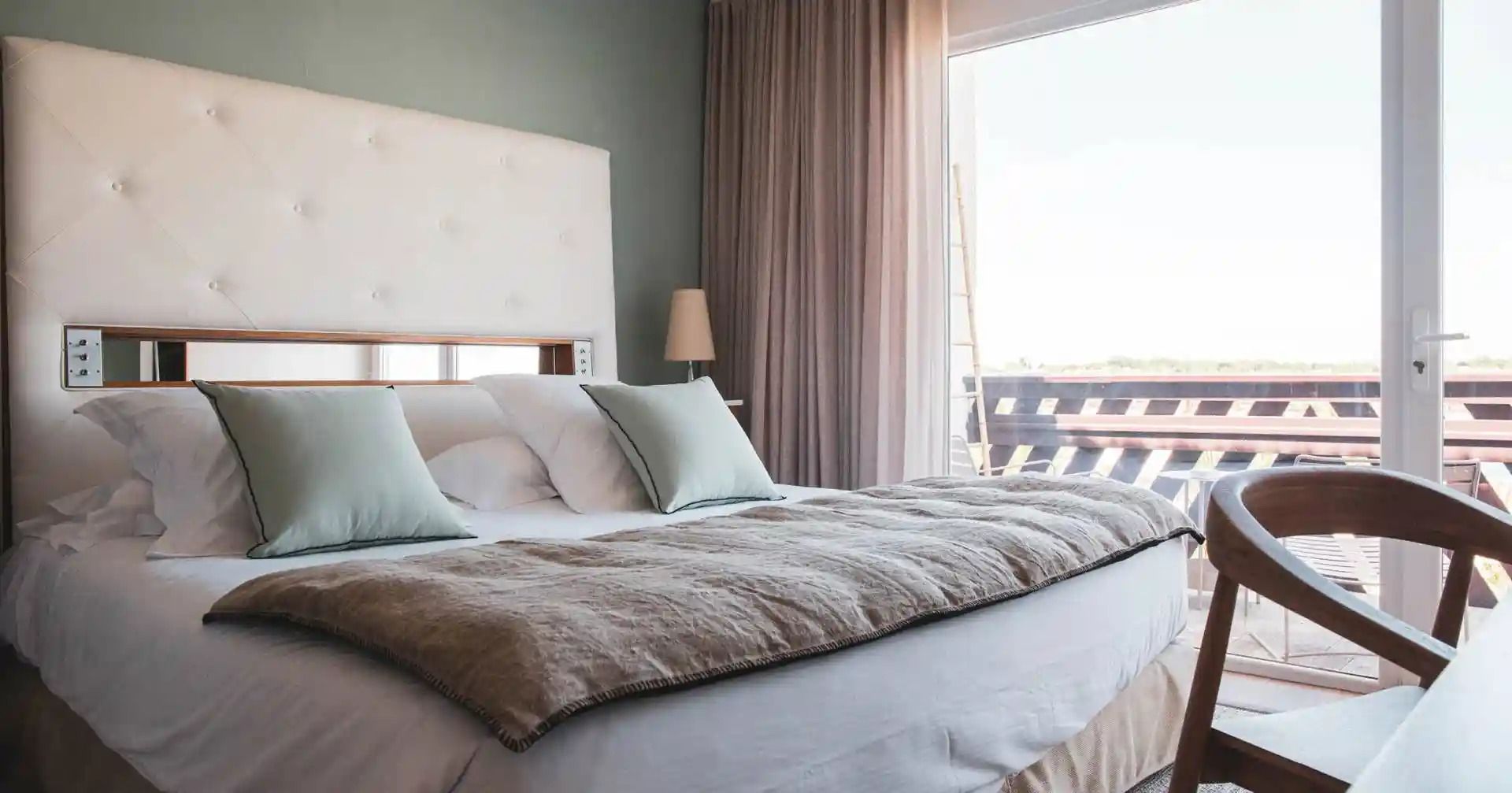 Ett hotellrum med en säng, kuddar, en sänglampa och utsikt över omgivningarna.
