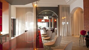 Een moderne hotellobby met een glazen scheiding, een zithoek en uitzicht op de eetruimte.