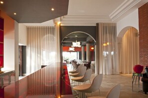 Un hall d’hôtel moderne avec une cloison en verre, un espace salon et une vue sur la salle à manger.